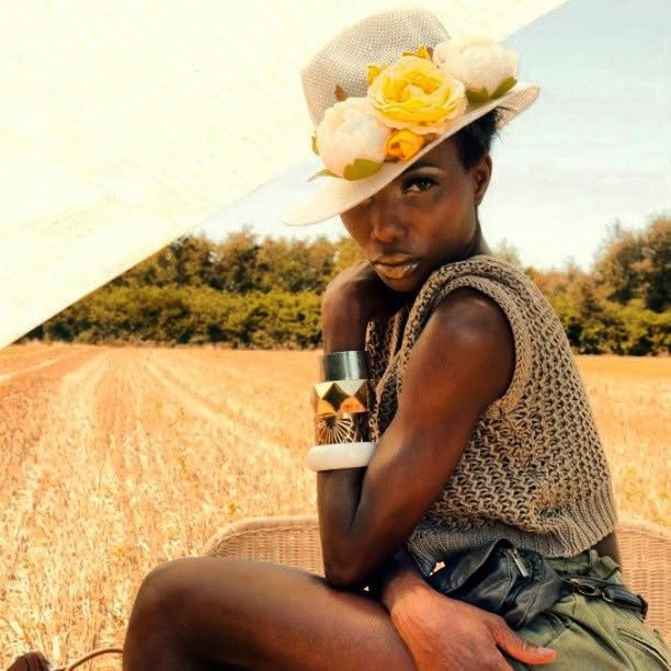 Modella con cappello di paglia e rose gialle in un campo di grano, editorial estivo