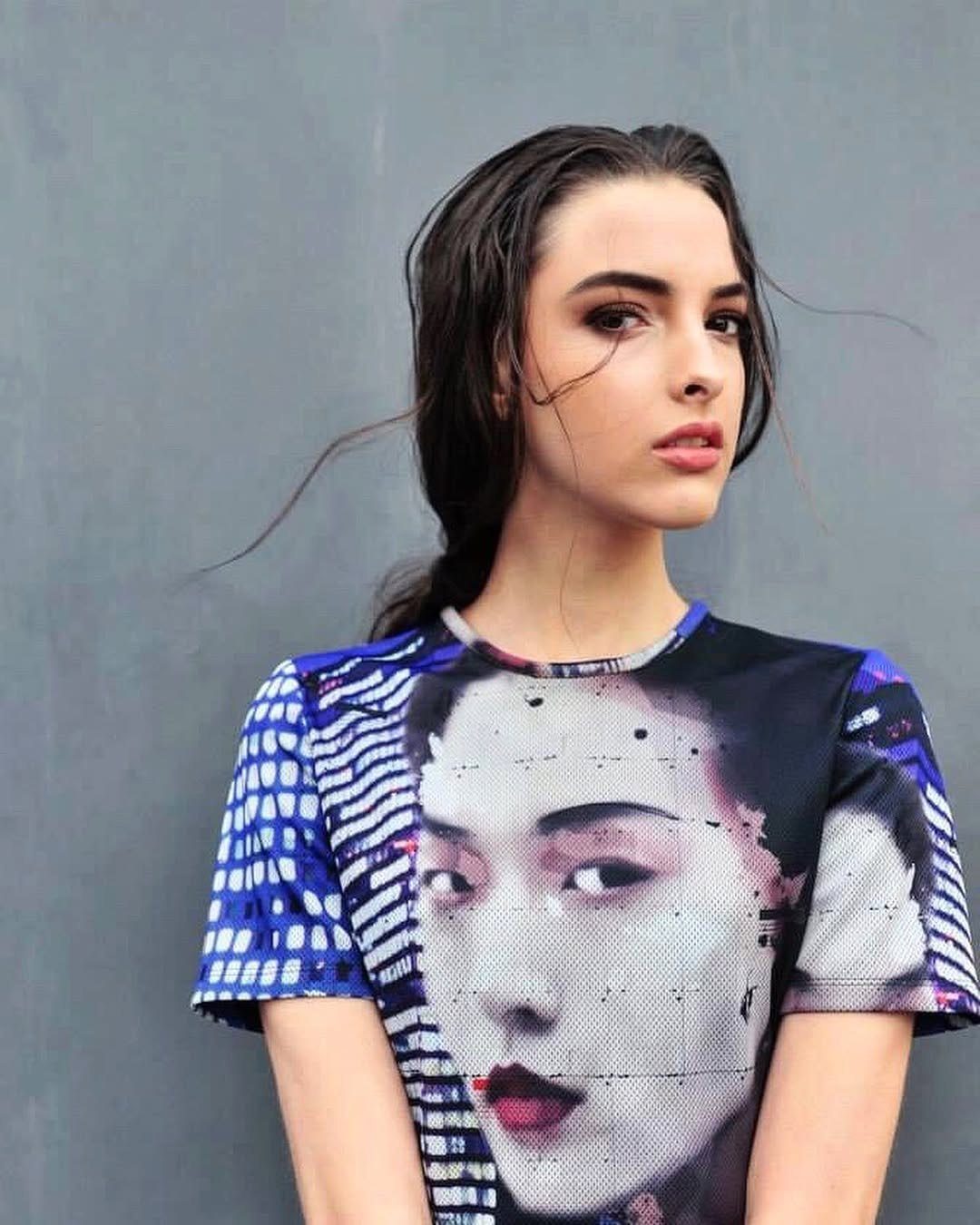 Modella con t-shirt stampata e trucco occhi intenso su sfondo grigio