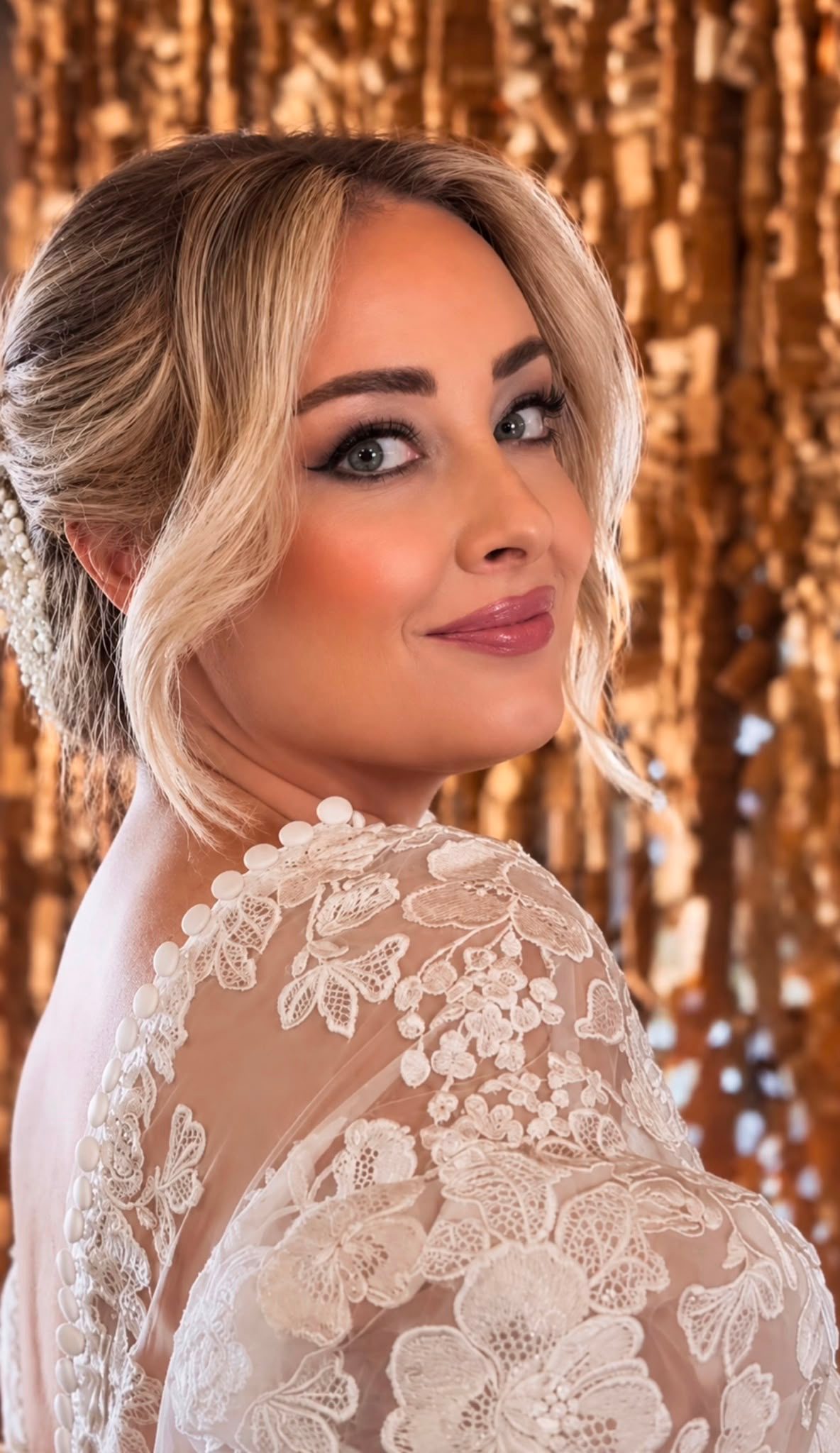 Sposa bionda con abito in pizzo, trucco occhi con eyeliner e labbra rosate